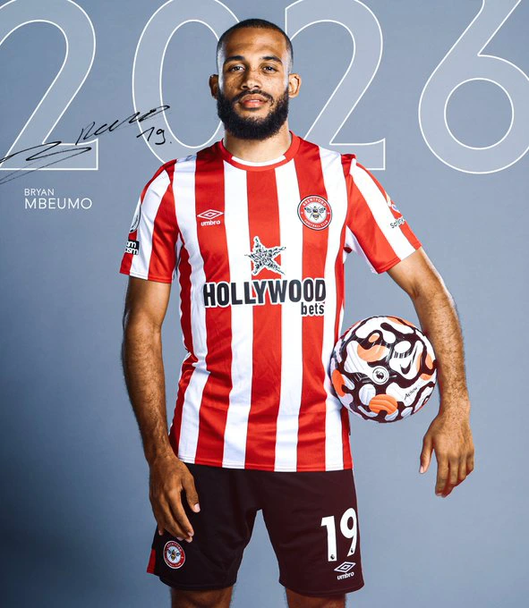 Bryan Mbeumo stands with a ball under his arm, dressed in the red and white stripes of Brentford FC. Above him, the number 2026.