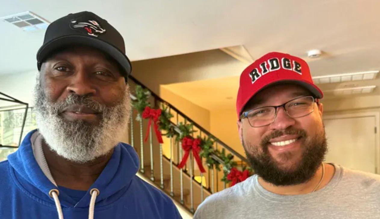 Lovie Smith and his son Miles Smith smiling indoors.