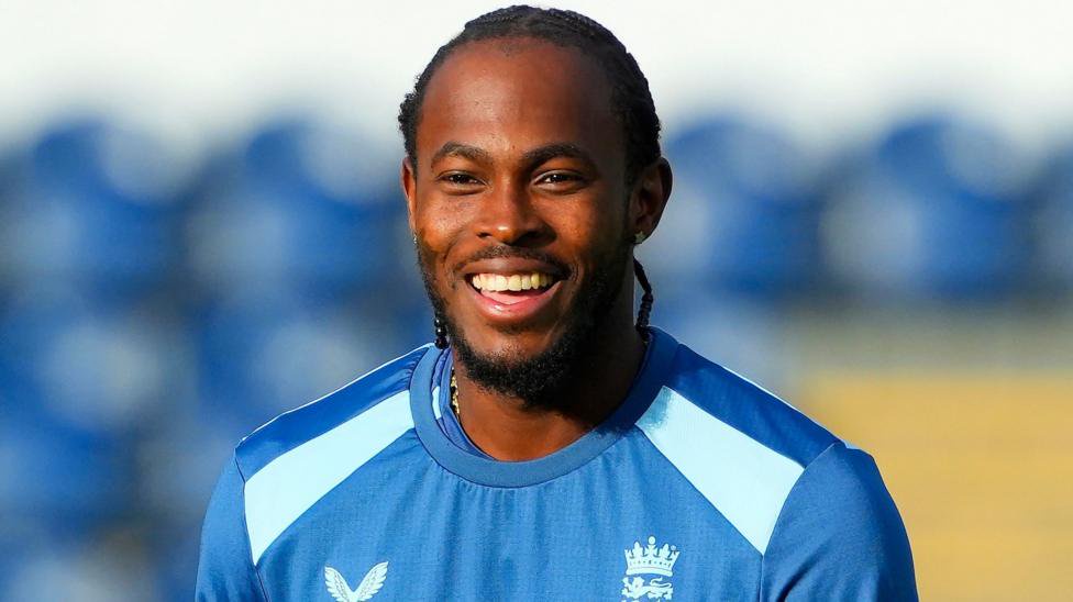 Jofra Archer wearing a blue England top smiles