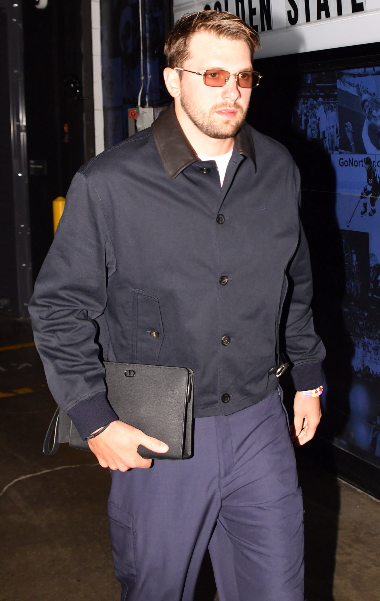 Luka Doncic arrives at the arena wearing a dark jacket and holding a black folder.