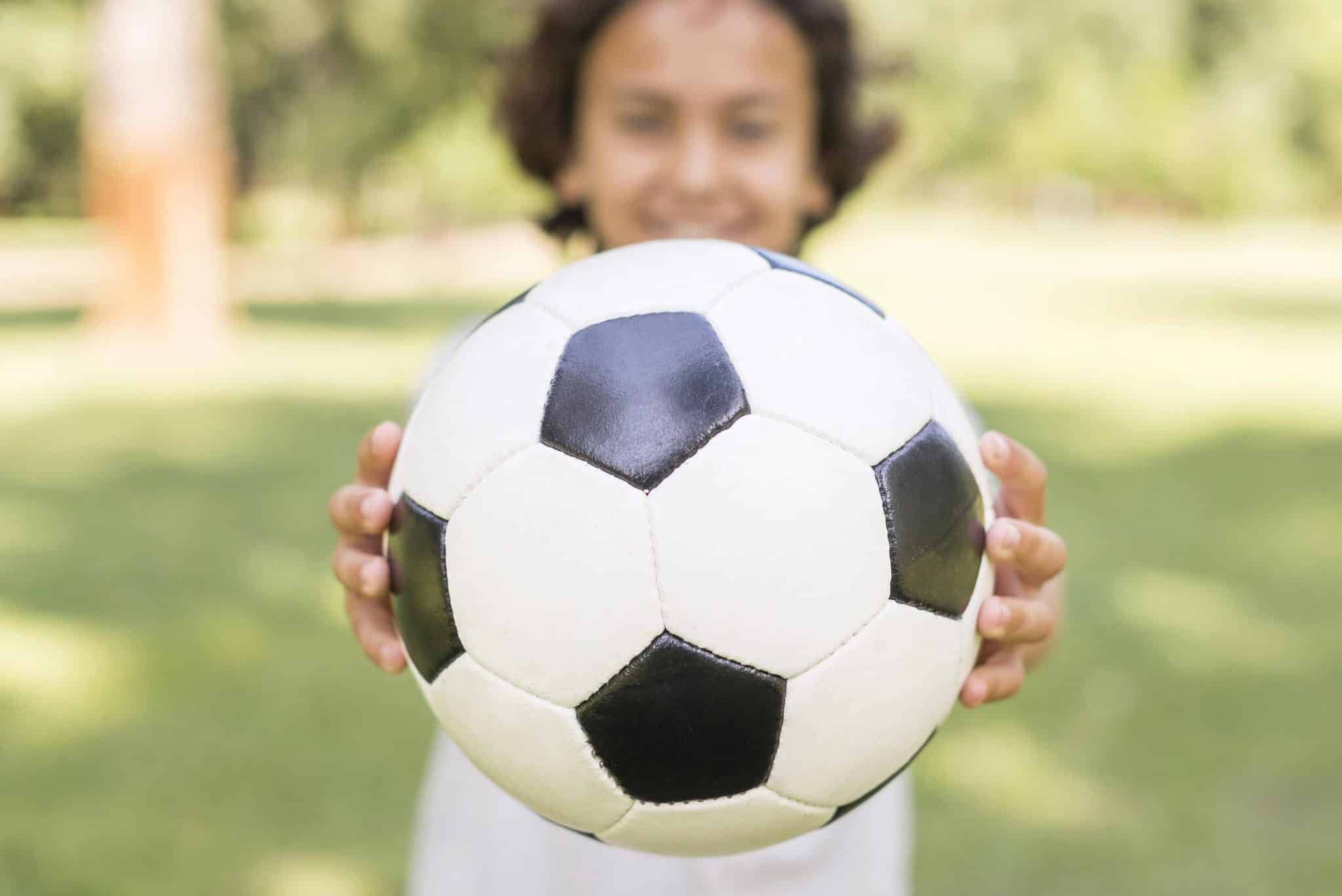 close up boy playing with football ball