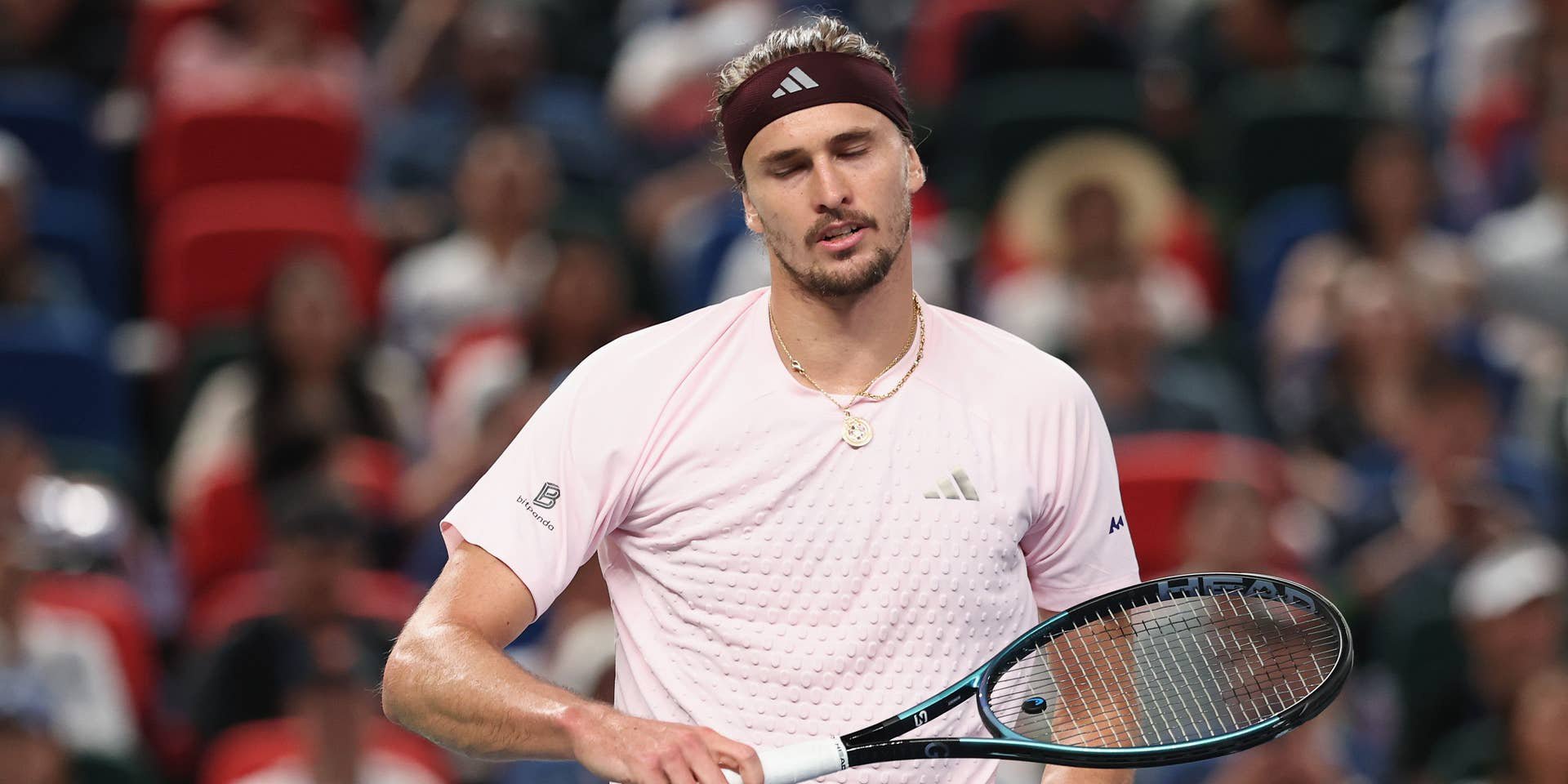 Ein Tennisspieler mit Stirnband und Schläger wirkt enttäuscht während eines Matches.