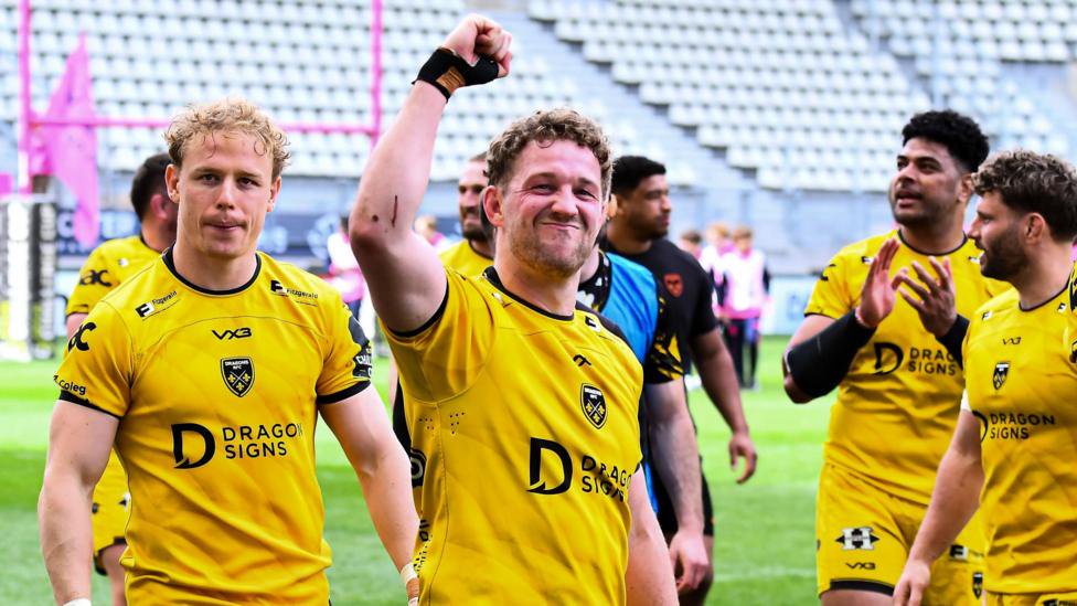 Angus O'Brien clenches a raised fist as Dragons players in amber celebrate