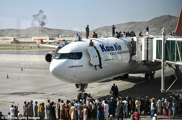 Afghan people climb atop a plane as they wait at the Kabul airport in Kabul on August 16, 2021, after a stunningly swift end to Afghanistan's 20-year war