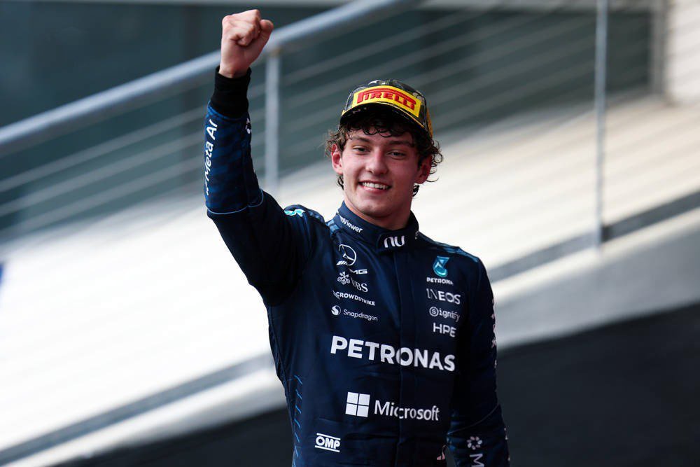 Mercedes driver in navy Petronas suit and Pirelli cap raises a fist on the podium, Formula 1 United States GP