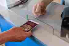 A passenger hands over their U.K. passport for inspection at a border control kiosk