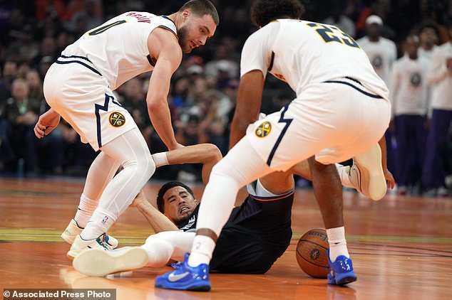 Phoenix Suns guard Devin Booker, bottom, has the ball stolen from him by Denver Nuggets guard Christian Braun (0) and forward Cameron Johnson (23) during the first half of an NBA Cup basketball game, Friday, Oct 30, 2026, in Phoenix. (AP Photo/Rick Scuteri)