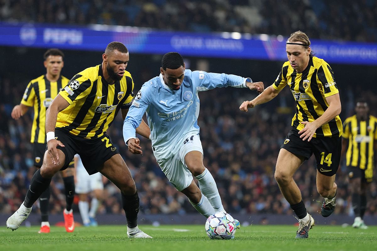 Allan of Manchester City is challenged by Harold Moukoudi of AEK Athens FC during the UEFA Champions League tie
