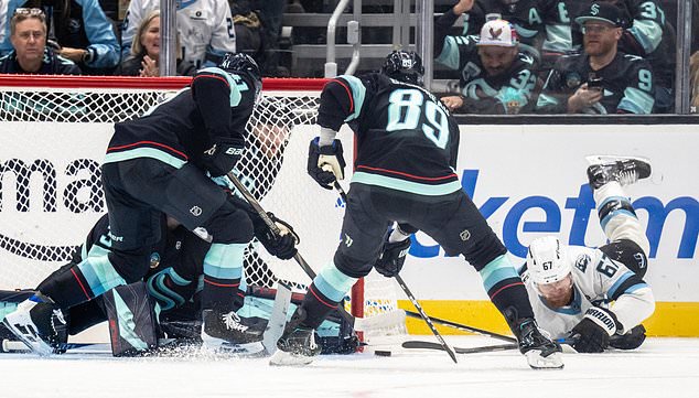 Utah Mammoth forward Lawson Crouse, right, loses control of the puck against Seattle Kraken defenseman Ryker Evans, left, and forward Frederick Gaudreau during the third period of an NHL hockey game, Thursday, Oct. 22, 2026, in Seattle. (AP Photo/Stephen Brashear)