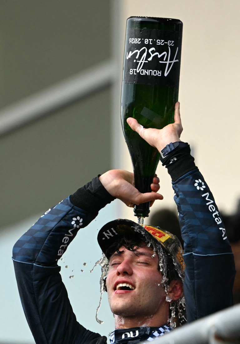 Mercedes driver Kimi Antonelli pours champagne over his head to celebrate his victory on the podium.
