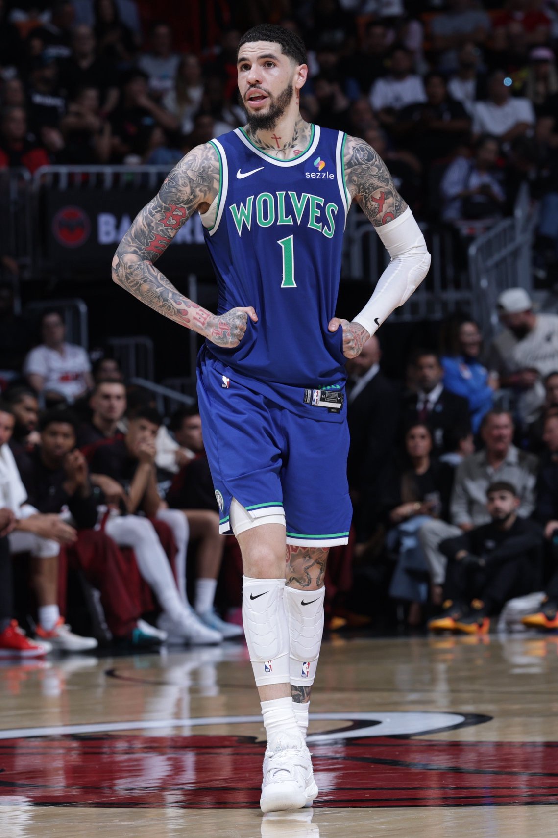 Basketball player in a Wolves jersey on the court, adorned with tattoos, actively engaged in a game