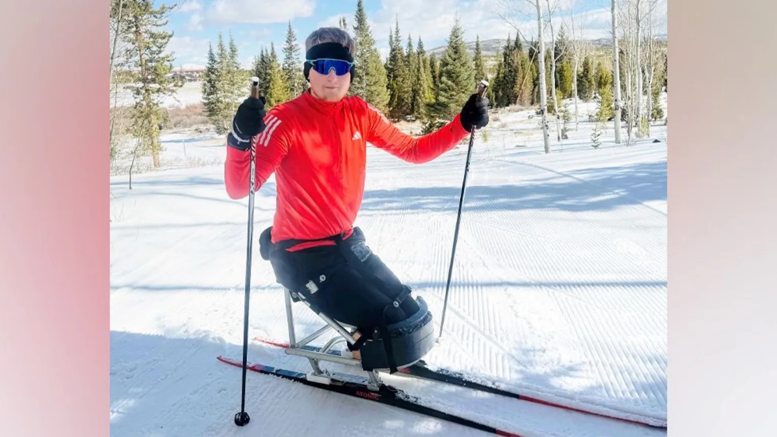 Adam Golebiewski Adam Golebiewski, a young man who has lost both legs, on skis in snow, he is smiling at the camera.