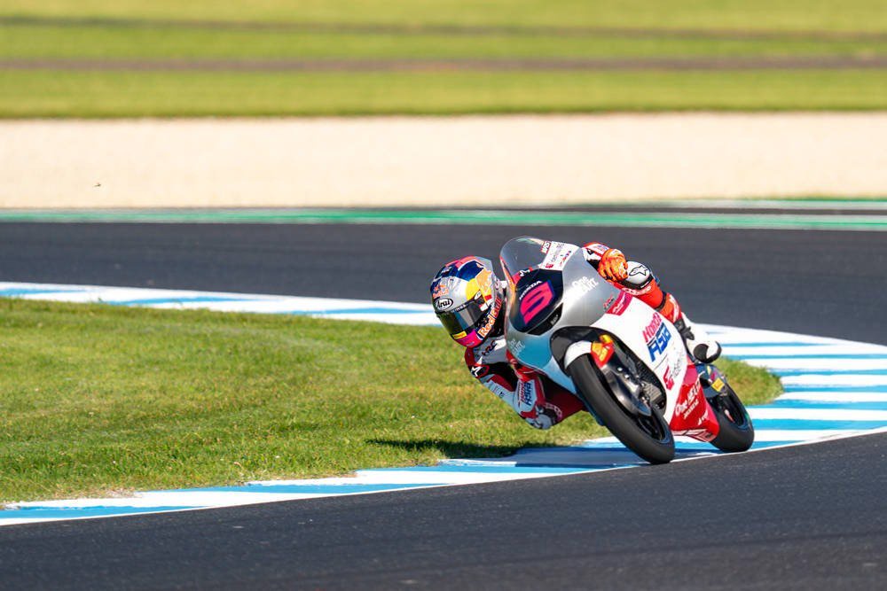 Moto3 rider in red and white leathers, number 9, leaning into a corner at Phillip Island, Australia, with a white and red bike.