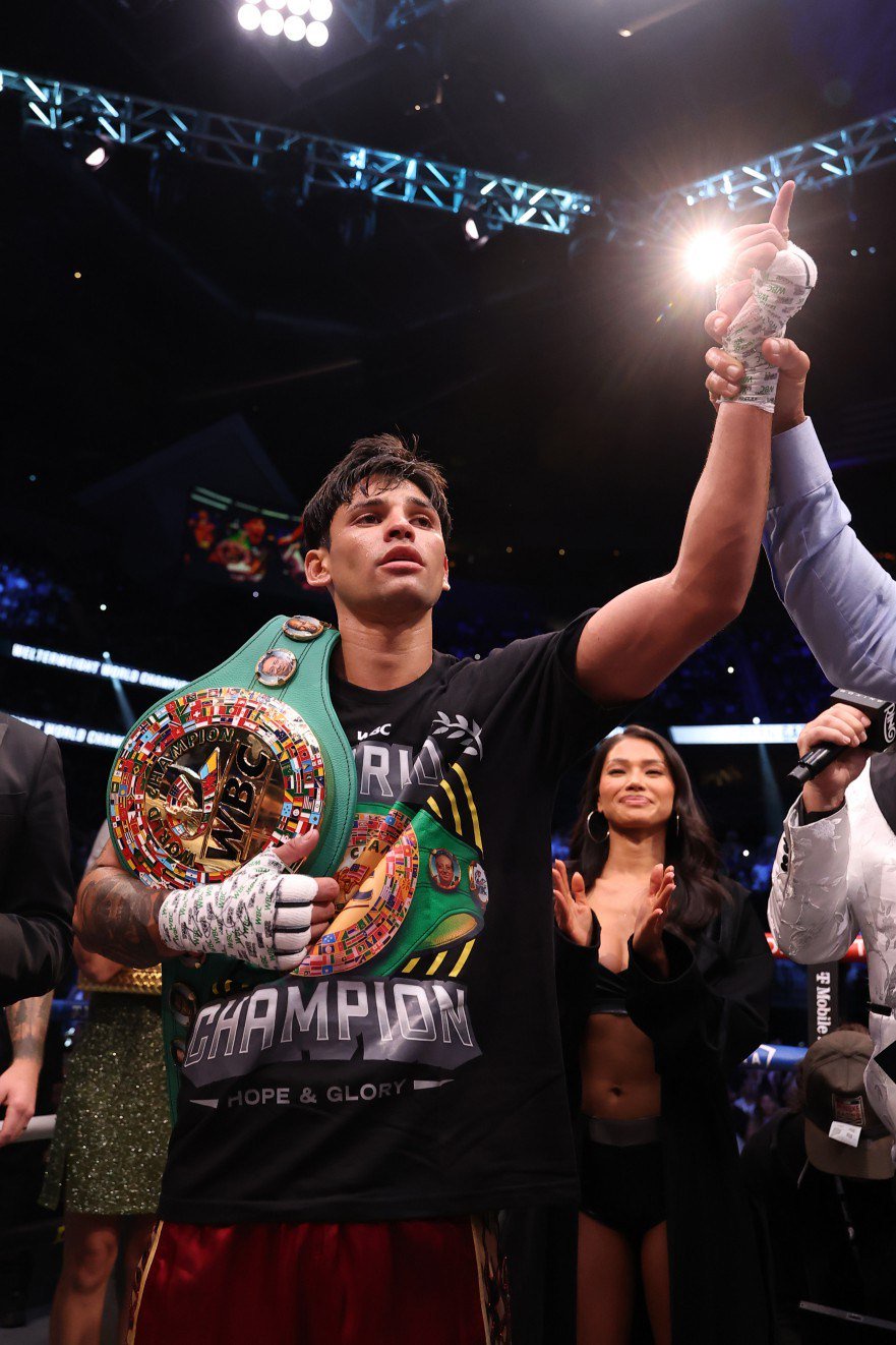Ryan Garcia holds up a championship belt in the ring.