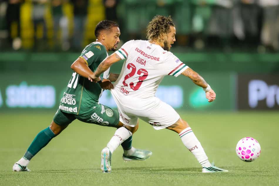 Guga (Fluminense) disputa a bola com jogador do time verde; bola rosa em campo.