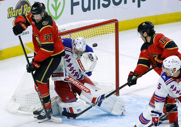 New York Rangers goaltender Dylan Garand, second from left, makes a save as Ottawa Senators' Warren Foegele (37), Senators' Shane Pinto (12) and Rangers' Sean Durzi (5) look on during the first period of an NHL hockey game in Ottawa, Ontario, Saturday, Oct. 24, 2026. (Patrick Doyle/The Canadian Press via AP)