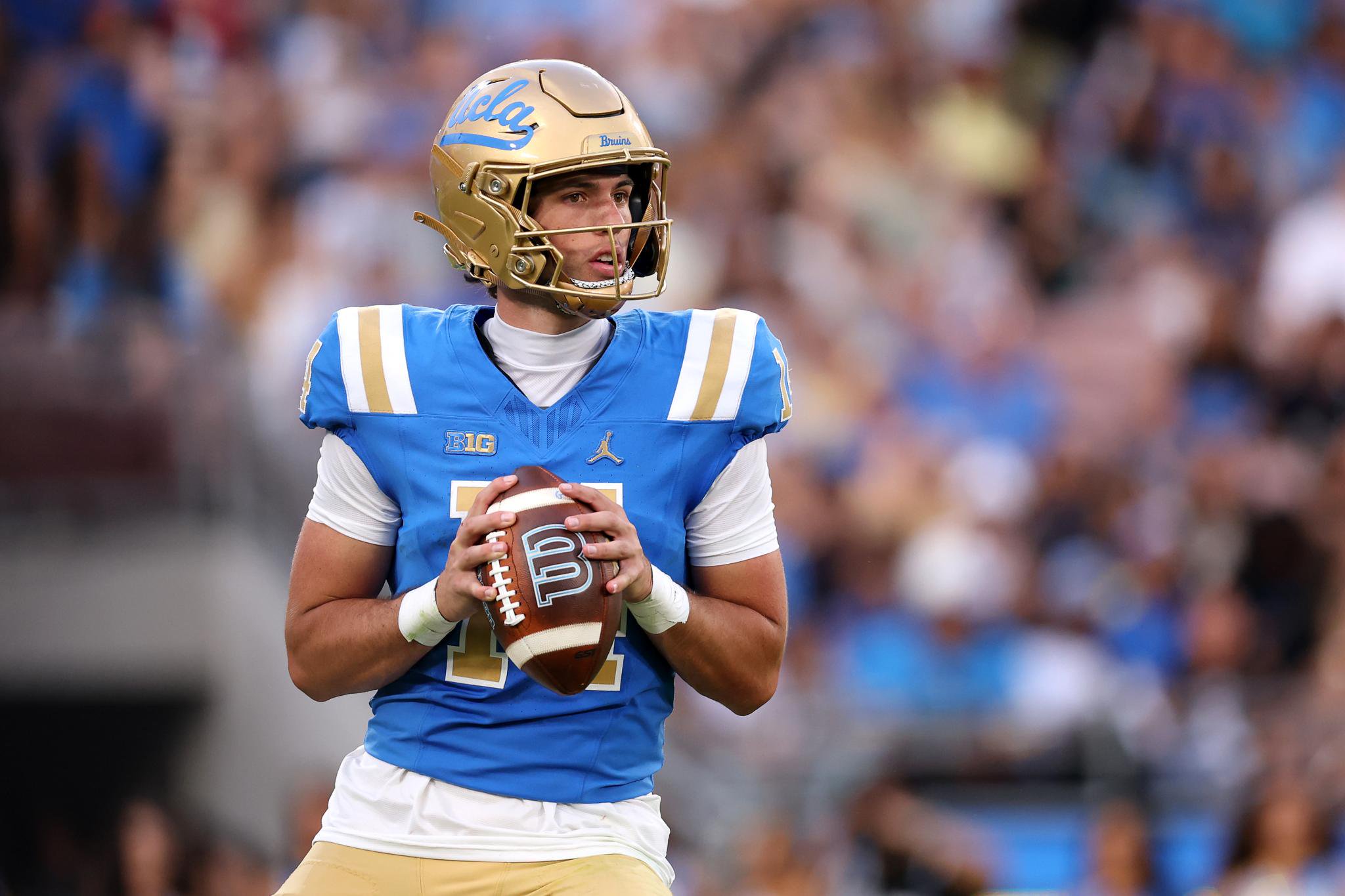 A UCLA football player holding a football during a game against Wisconsin.
