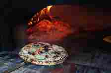 Emma Schwendeman of Flour Girl & Flame pulls a pizza...