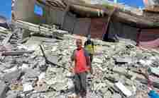 Grey-haired man standing on a pile of rubble in the sun