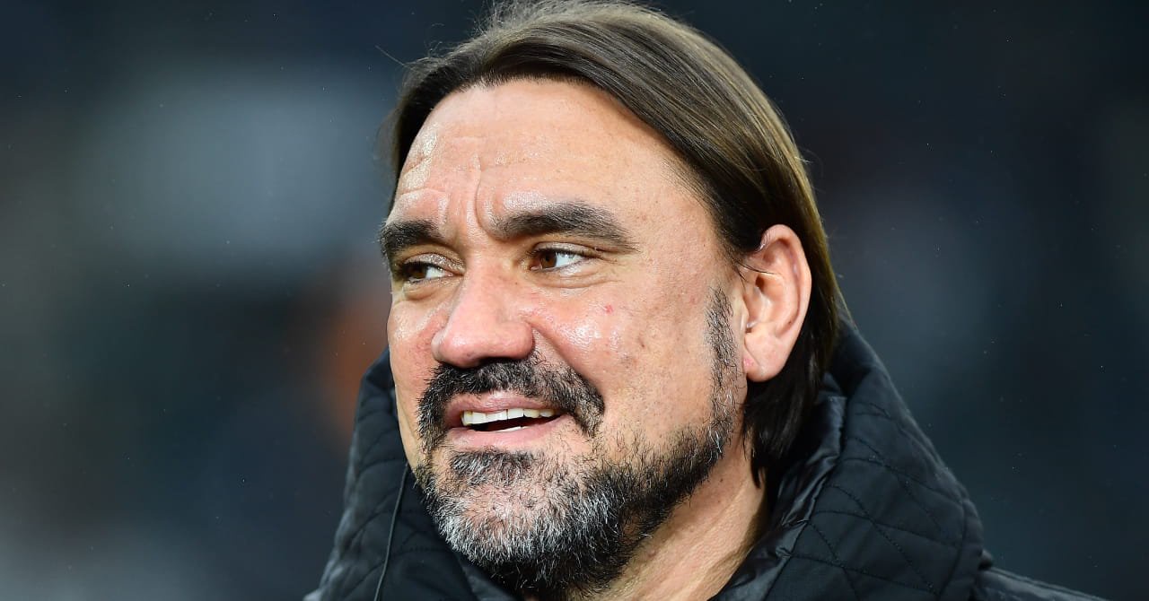 Manager Daniel Farke looking to his right and smiling while wearing a black coat in a stadium as head coach of Premier League team Leeds United Football Club
