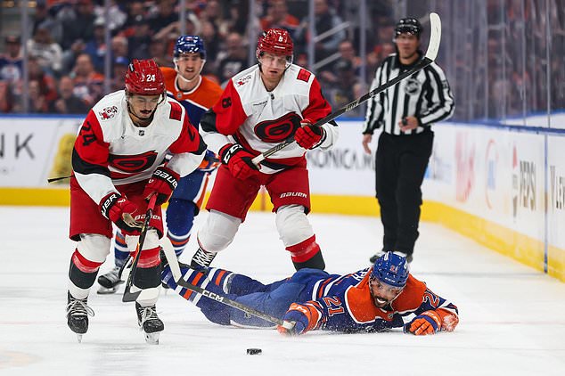 Edmonton Oilers' Mathieu Joseph (21) battles against Carolina Hurricanes' Seth Jarvis (24) and Juuso Valimaki (8) during the second period of an NHL hockey game in Edmonton, Alberta, Thursday, Oct. 22, 2026. (Codie McLachlan/The Canadian Press via AP)
