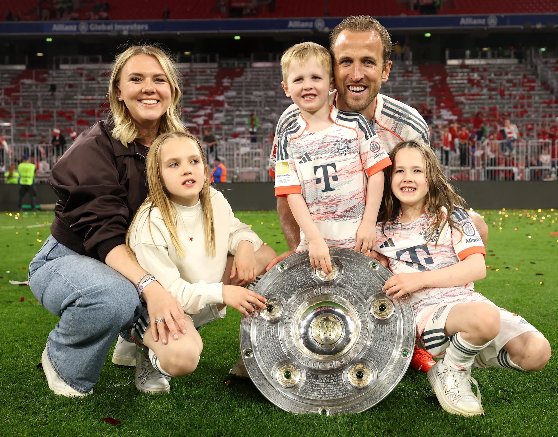 MUNICH, GERMANY - MAY 10: Harry Kane of Bayern Munich pose for a photo with the with the Meisterschale trophy, his wife Katie Goodland and their children, after the teams 2-0 victory in the Bundesliga match between FC Bayern München and Borussia…