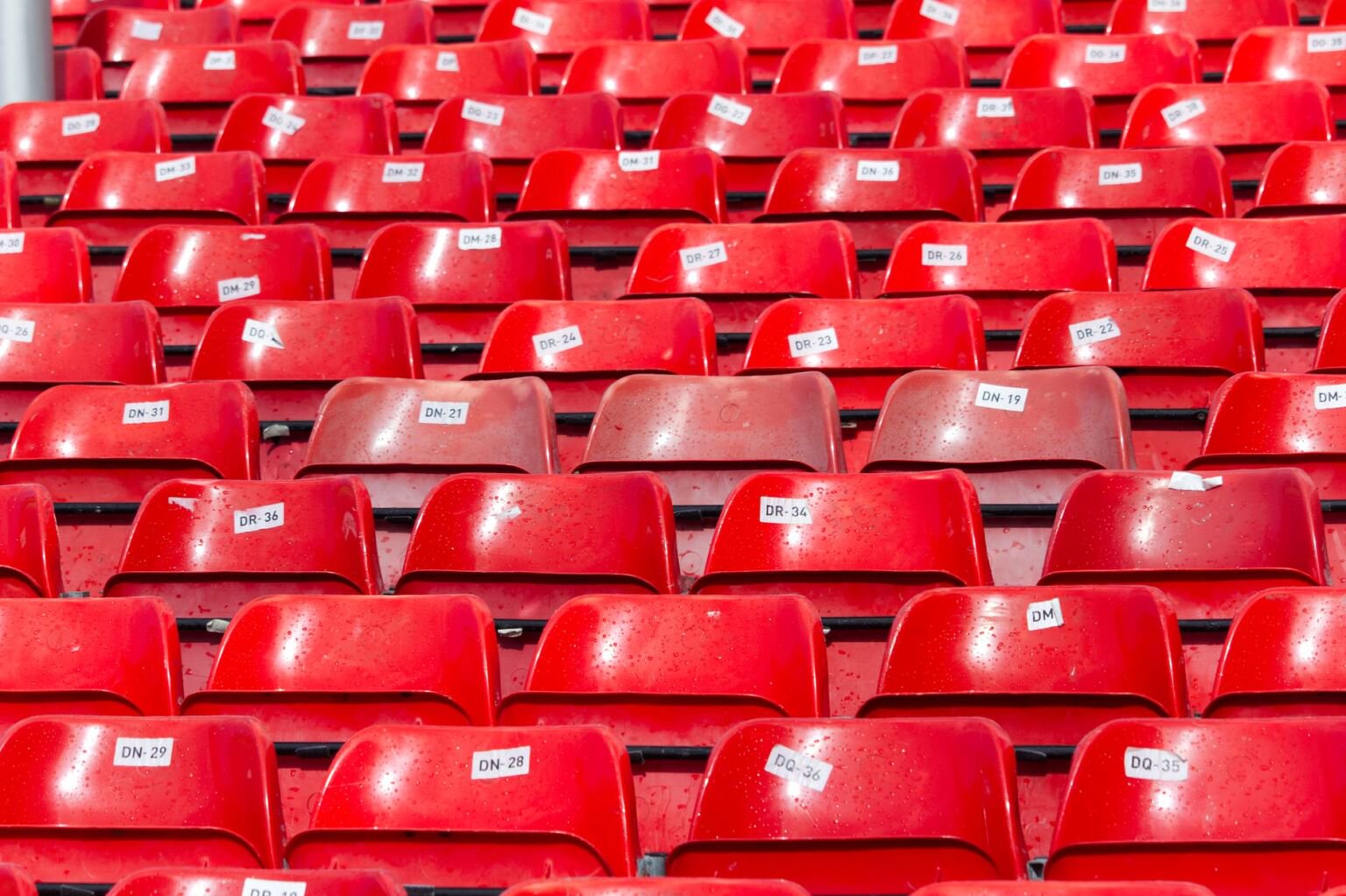 Rows of empty red stadium seats with numbered labels before a Manchester United home fixture