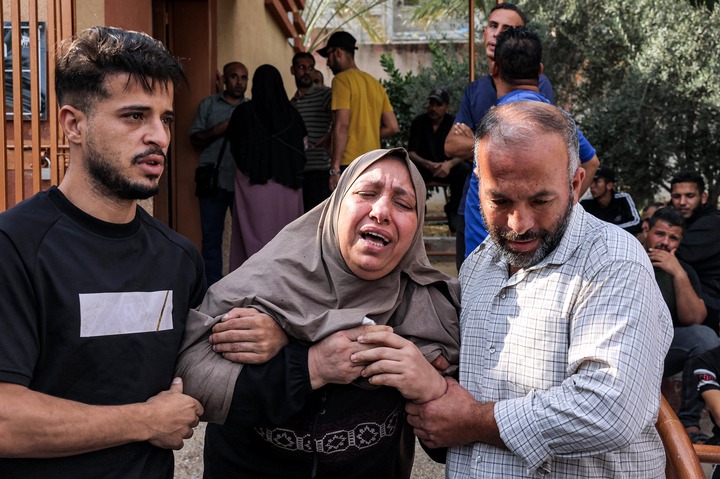 Men console a woman mourning for loved ones killed in an Israeli air strike outside a morgue in Khan Yunis in the southern Gaza Strip on October 11, 2023