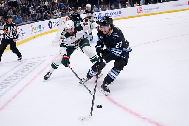 Utah Mammoth center Barrett Hayton (27) and Minnesota Wild center Yakov Trenin (13) battle for the loose puck during the second period of an NHL hockey game Tuesday, Oct. 27, 2026, in Salt Lake City. (AP Photo/Tyler Tate)