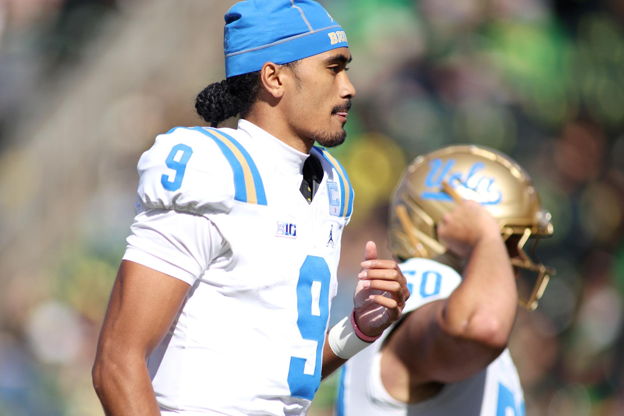 Nico Iamaleava on the field in a white jersey and blue cap.