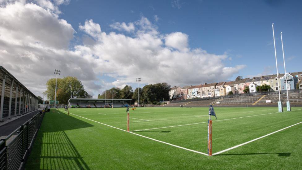 Wide view of St Helen's across the pitch from one corner with stands to the left and the far side and terracing in front of houses to the right