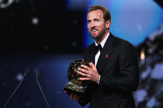 Image: Harry Kane wearing a tuxedo and holding the Ballon d'Or award.
