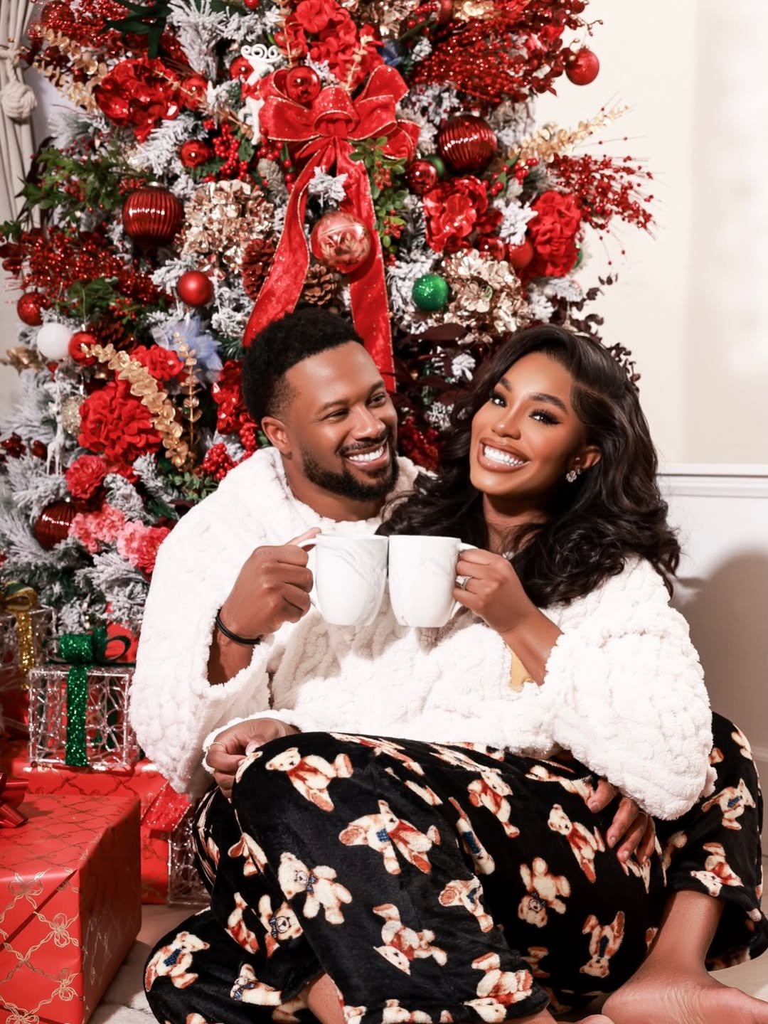 Nollywood actress Sharon Ooja poses with her husband in cosy Christmas outfits while holding mugs beside a decorated tree