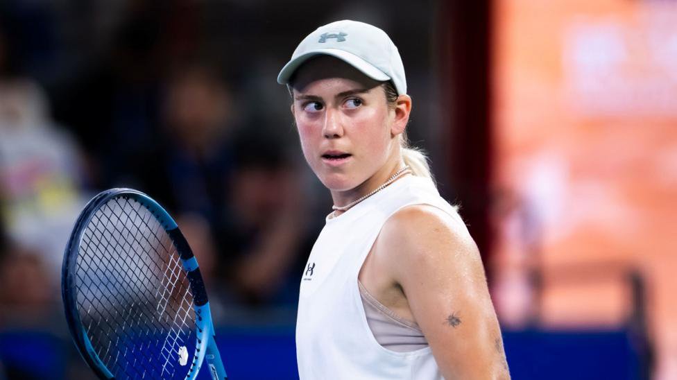 Sonay Kartal, wearing a white, sleeveless tennis shirt and white cap, looks to her left
