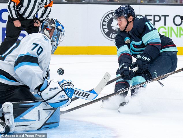 Seattle Kraken forward Mackie Samoskevich, right, fights Utah Mammoth goalie Karel Vejmelka for a loose puck in front of the net during the third period of an NHL hockey game, Thursday, Oct. 22, 2026, in Seattle. (AP Photo/Stephen Brashear)