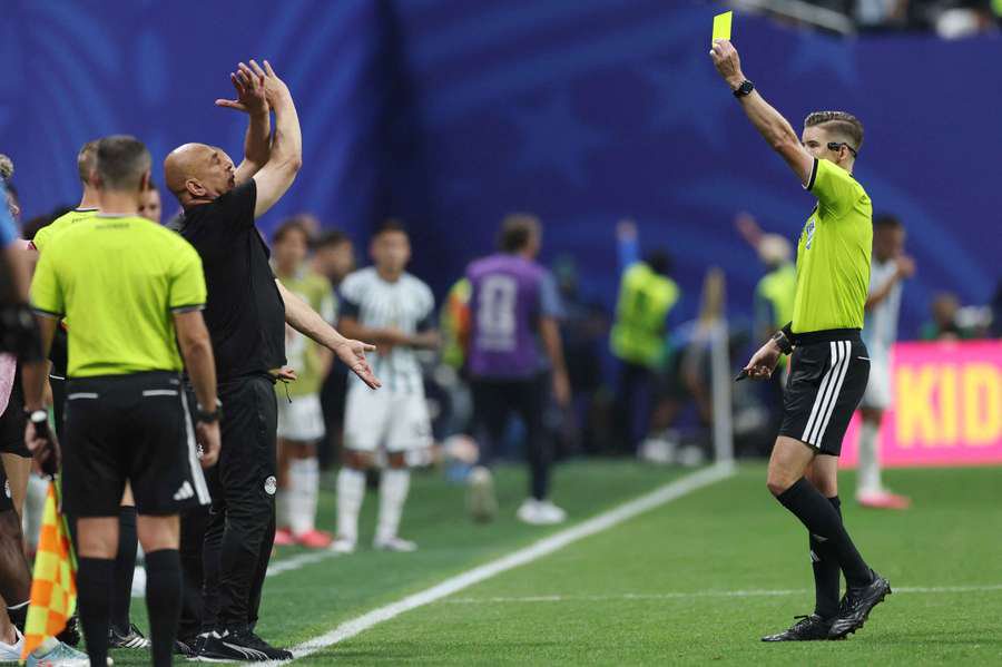 Egypt coach Hossam Hassan is shown a yellow card by referee Francois Letexier during the match with Argentina