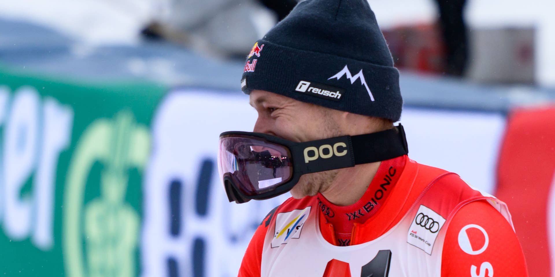 Ein Skifahrer feiert auf dem Podium mit einer spritzenden Champagnerflasche im Schnee.