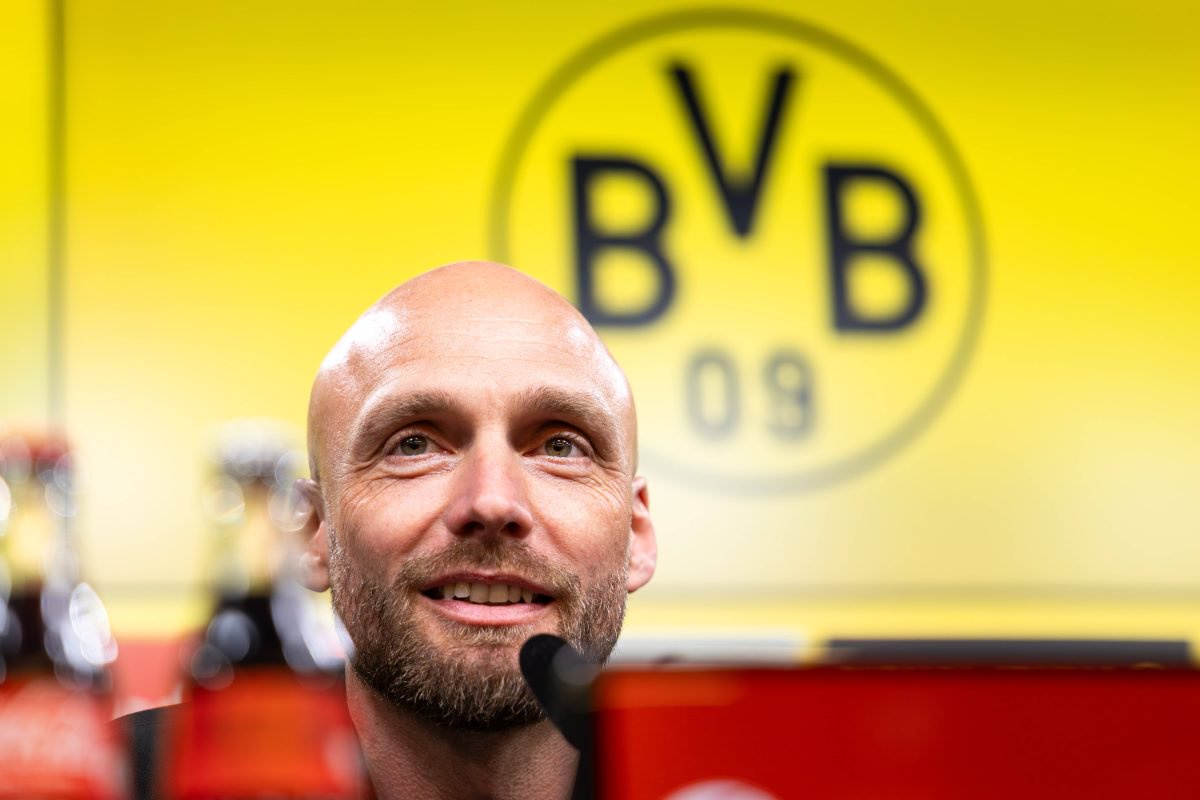 Ole Book vor einem BVB-Logo.