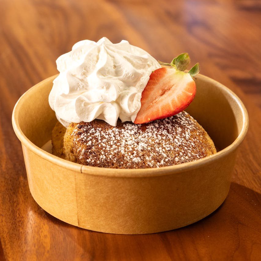 Dessert served in a bowl with whipped cream and a strawberry.