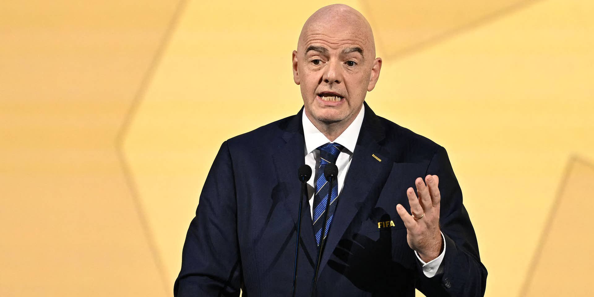 Ein Mann im Anzug spricht bei einem FIFA-Kongress an einem Podium mit FIFA-Logo.