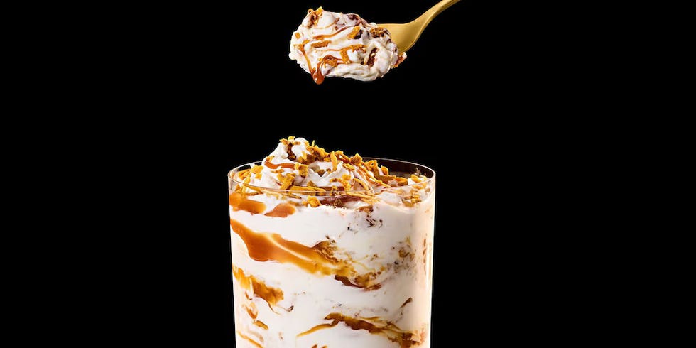 Caramel swirl dessert in a glass with a spoonful above on a black background.