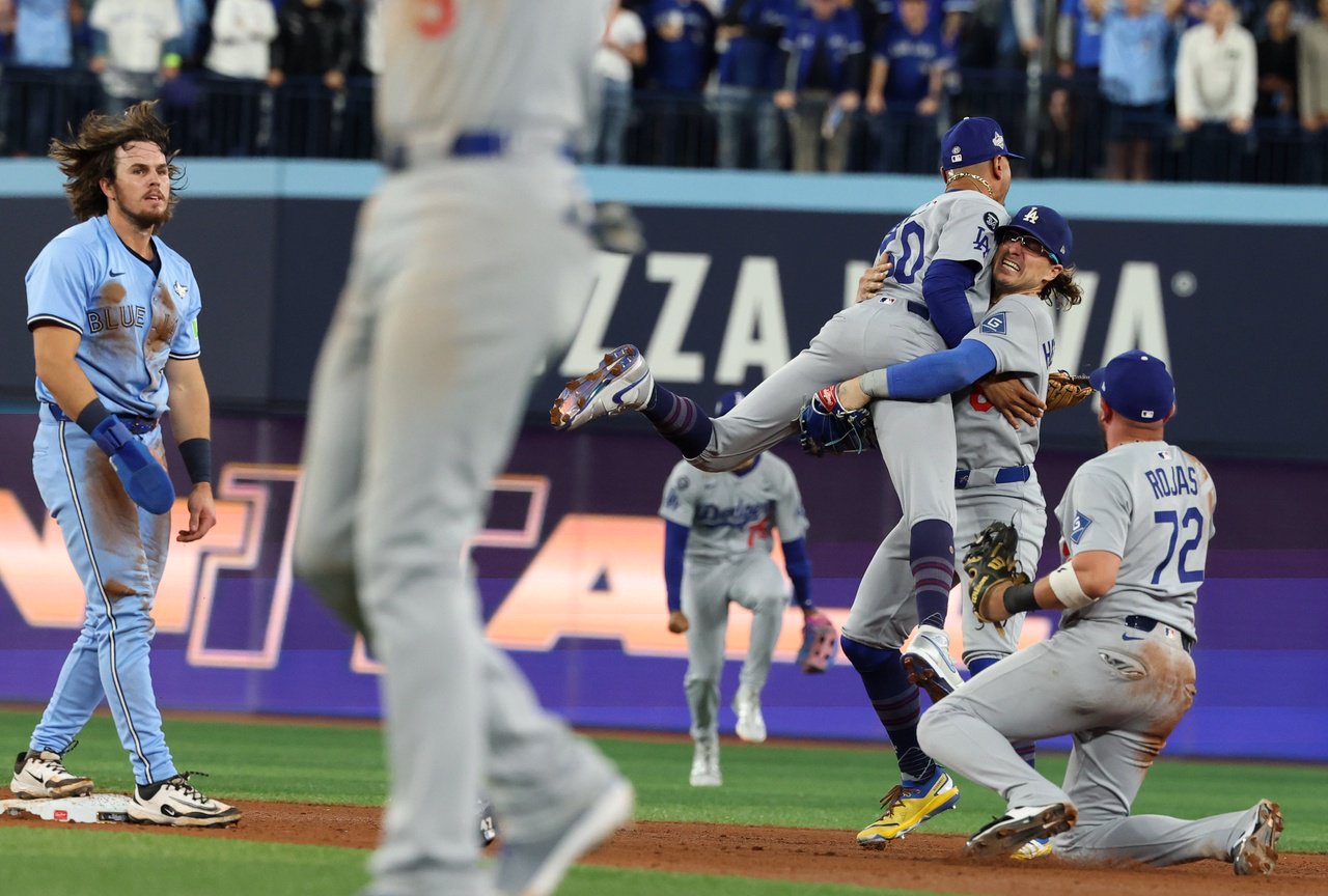 Toronto, Ontario, Friday, October 31, 2025 - Los Angeles Dodgers shortstop Mookie Betts (50) jumps into the arms of Los Angeles Dodgers first baseman Enrique Hernández (8) as Dodgers second baseman Miguel Rojas (72) reacts after Hernandez threw to Rojas at second to get the out on Toronto Blue Jays' Addison Barger, left, to end the game with a double play and the win in Game six of the 121st World Series between the LA Dodgers and the Toronto Blue Jays at Rogers Centre. (Robert Gauthier/Los Angeles Times via Getty Images)
