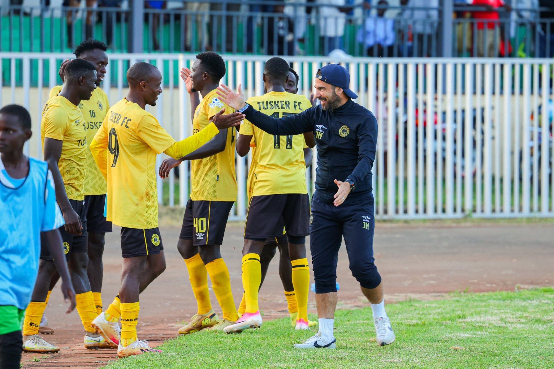 Tusker FC squad members and coaching staff celebrating together at the stadium.