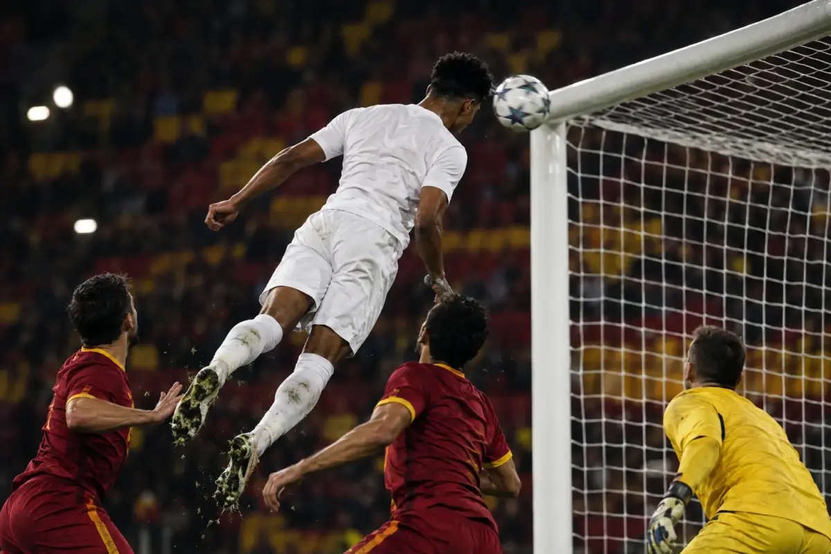 Young forward scoring a dramatic headed equaliser in a European football match