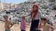 BBC Asmahan stands with three of her grandchildren in front of a giant rubbish heap