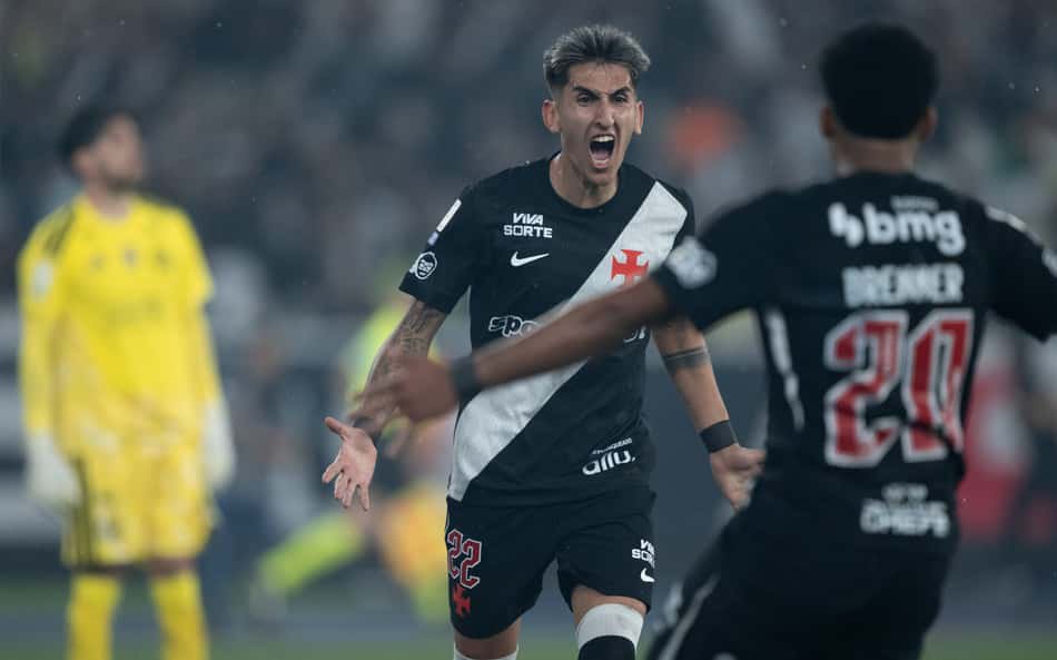Jogador do Vasco da Gama, em uniforme preto com faixa diagonal branca, comemora com os braços abertos durante a partida.
