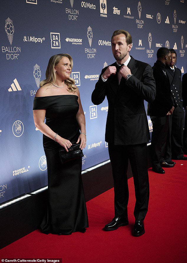 Katie shoots her husband an adoring glance as he adjusts his bow-tie on the red carpet last night