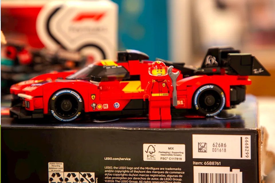 LEGO race car model with a mechanic figure holding a wrench, displayed on a box with various branding elements.