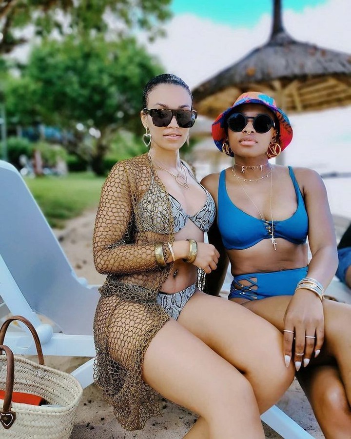 This may contain: two beautiful women sitting next to each other on a beach