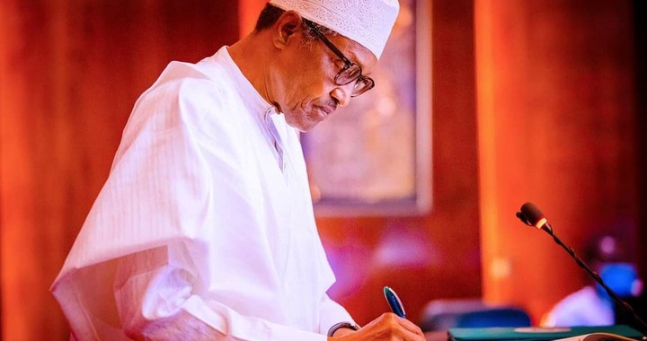 Buhari signs the document at the State House, Abuja